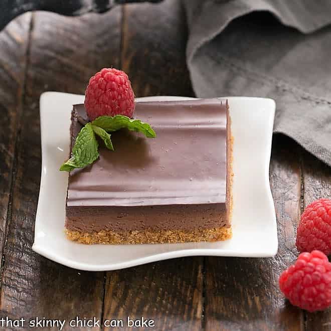 A slice of Dark Chocolate Mousse Bars on a white plate topped with a raspberry