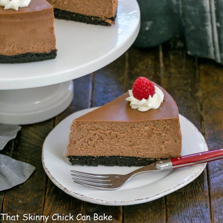 Slice of chocolate mascarpone cheesecake with a red handled fork on a white plate.