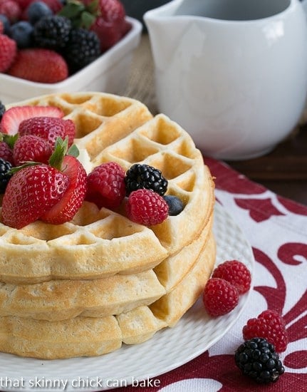 Homemade Buttermilk Waffles stacked on a white ceramic plate with a trio of berries.