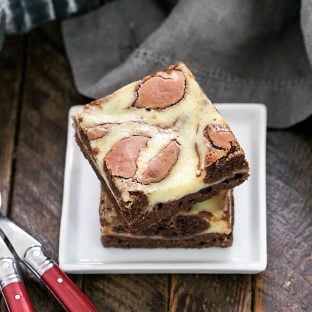 Stack of two Cheesecake Swirl Brownies on a square white plate with two forks