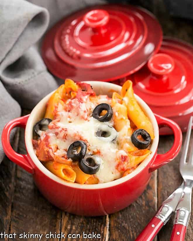 Overhead view of cheesy pasta bake in a small red crock.