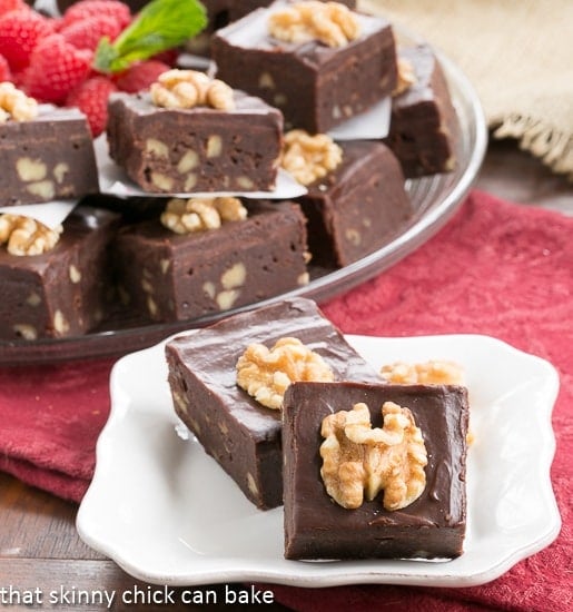 Chocolate Glazed Walnut Brownies on a small square white plate in front of the serving platter.