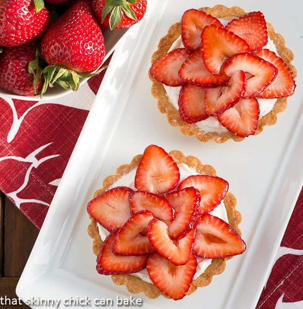 Overhead view of 2 Fresh Strawberry Tarts on white platter.