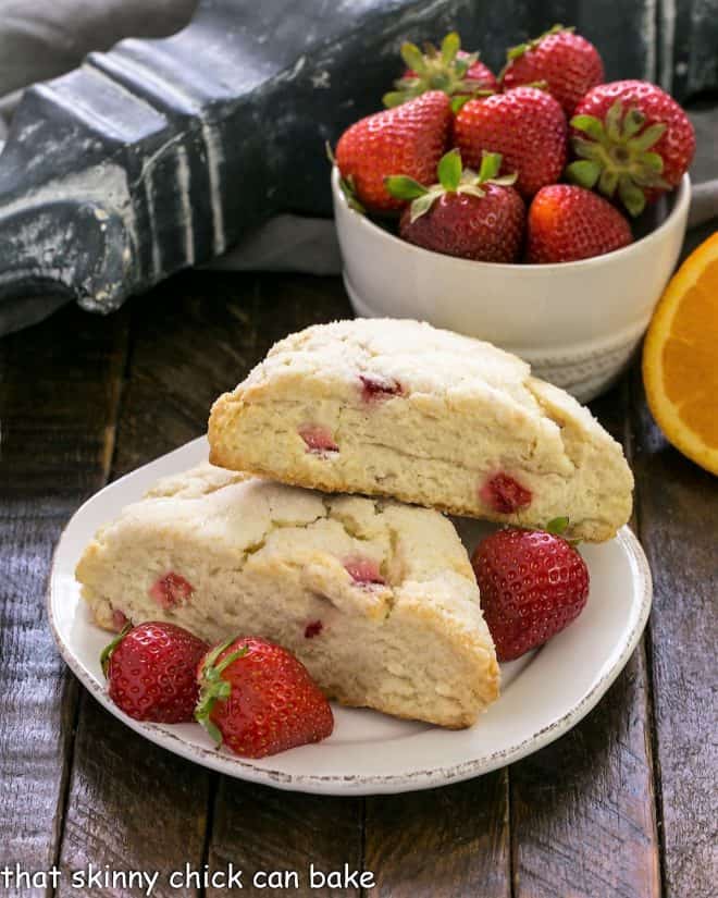 2 scones on a round white plate with fresh strawberries