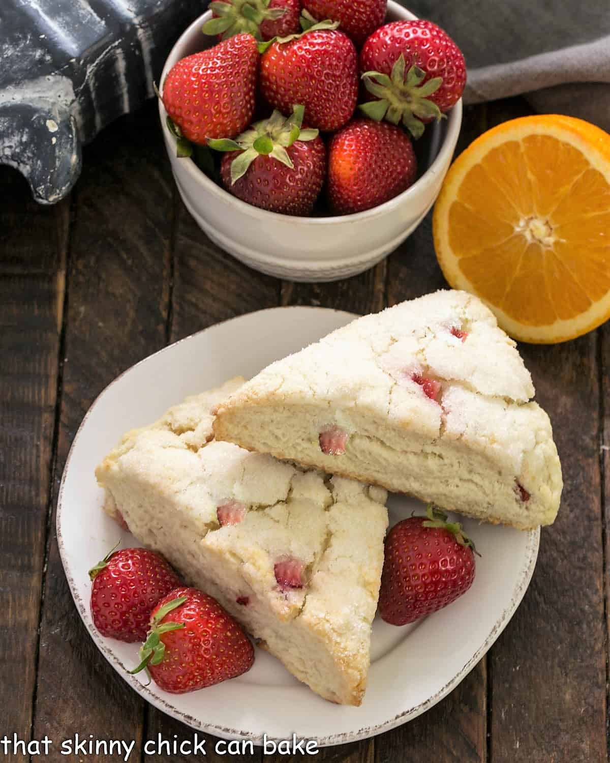 Overhead view of 2 Strawberry Buttermilk Scones on a small white plate with fresh strawberries.