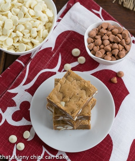 Overhead view of Butterscotch Blondies with White Chocolate Chips stacked on a white plate on a red and white napkin