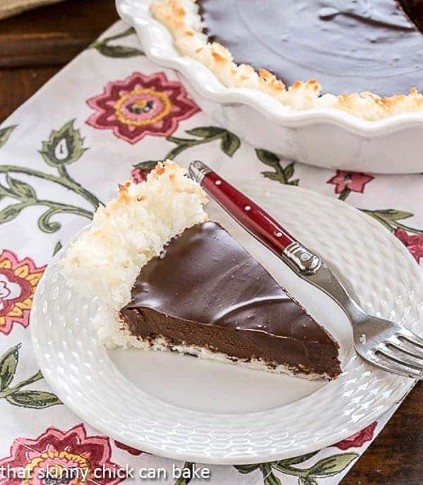 A slice of Coconut Crusted Chocolate Ganache Pie on a white plate with a red handled fork