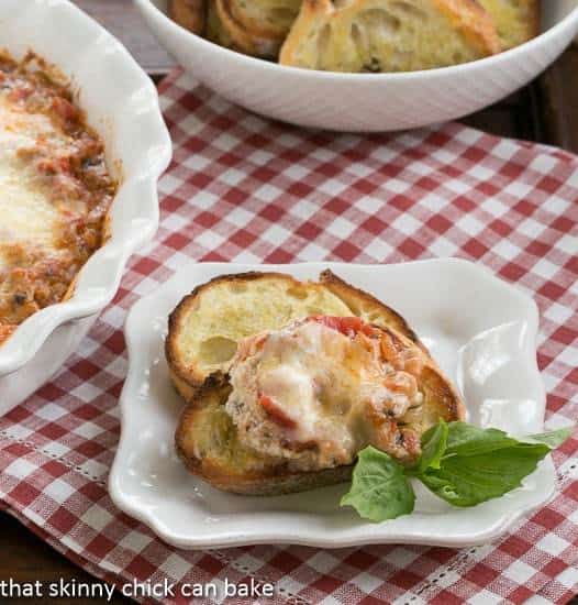 Cheesy Lasagna Dip with Sausage on a toast with a sprig of basil