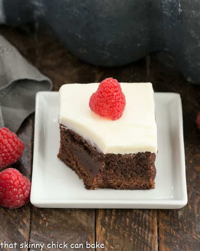 A raspberry brownie on a white plate with a bite removed.