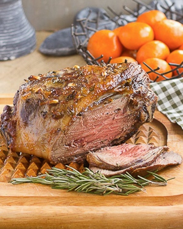 Glazed Leg of Lamb with Garlic and Rosemary on a cutting board.