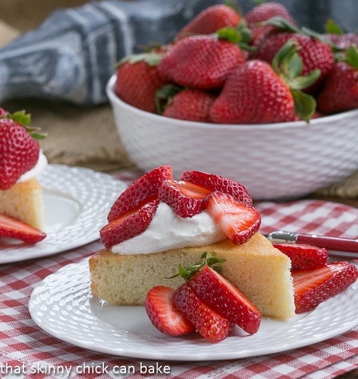 Slice of French Visitadine Cake on a white plate topped with berries and whipped cream