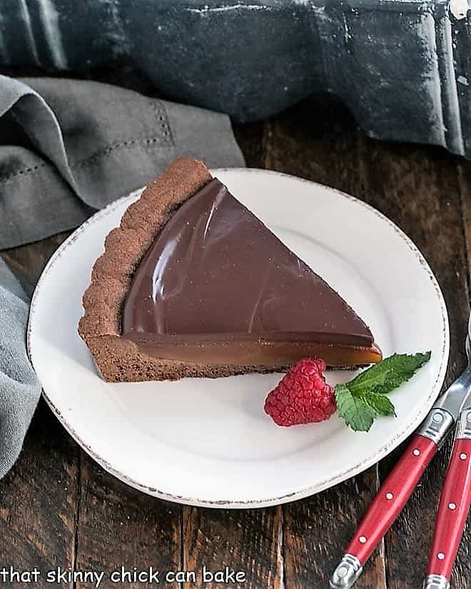 Chocolate Caramel Tart - A sublime pairing of chocolate and caramel! Slice of a Chocolate Caramel Tart on a white plate.
