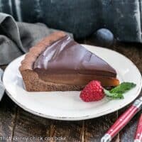 Slice of caramel tart on a plate with a raspberry and mint garnish