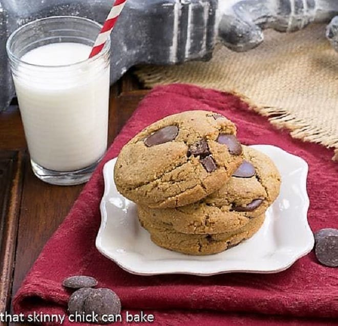 Jumbo Chocolate Chips stacked on a white square plate with a glass of milk