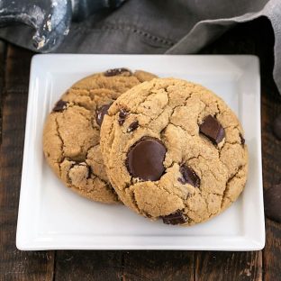 Two umbo chocolate chip cookies on a square white plate