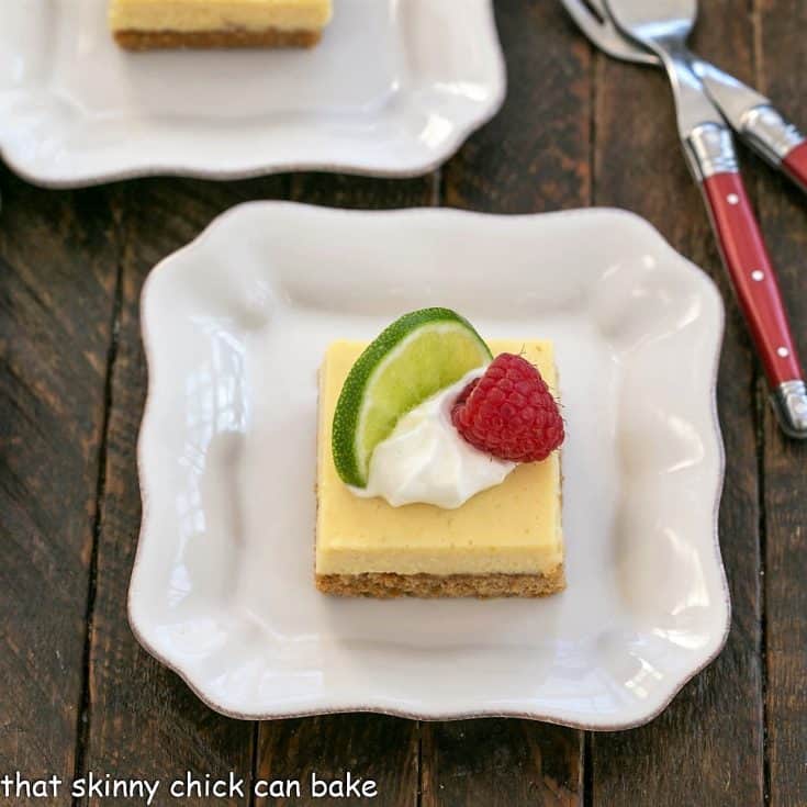 Overhead view of a key lime pie bar with a dollop of whipped cream, slice of lime and raspberry to garnish