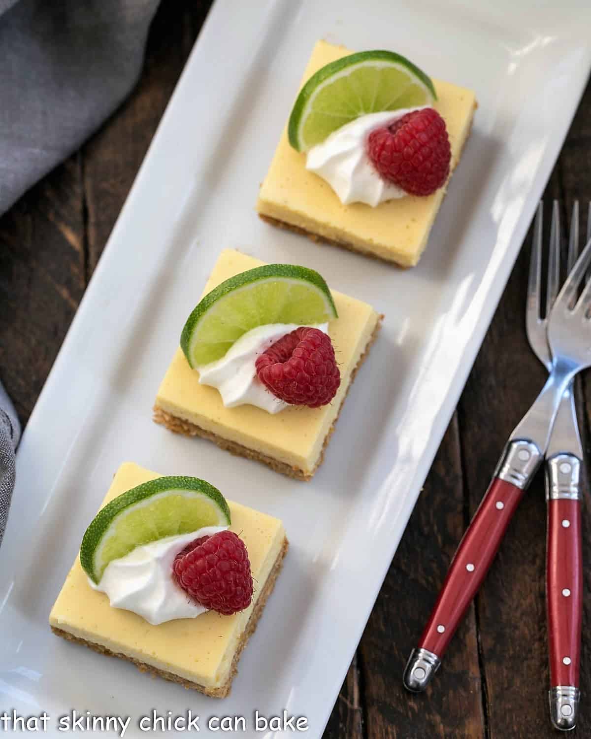 overhead view of 3 key lime pie bars on a white ceramic tray.