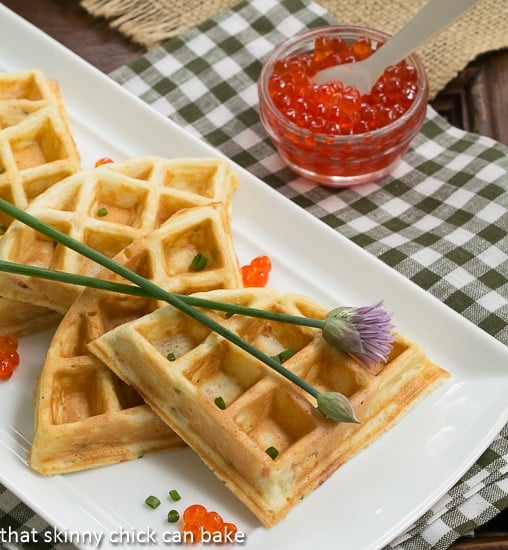 Smoked Salmon Waffles on a white platter with chives and salmon roe garnishes.