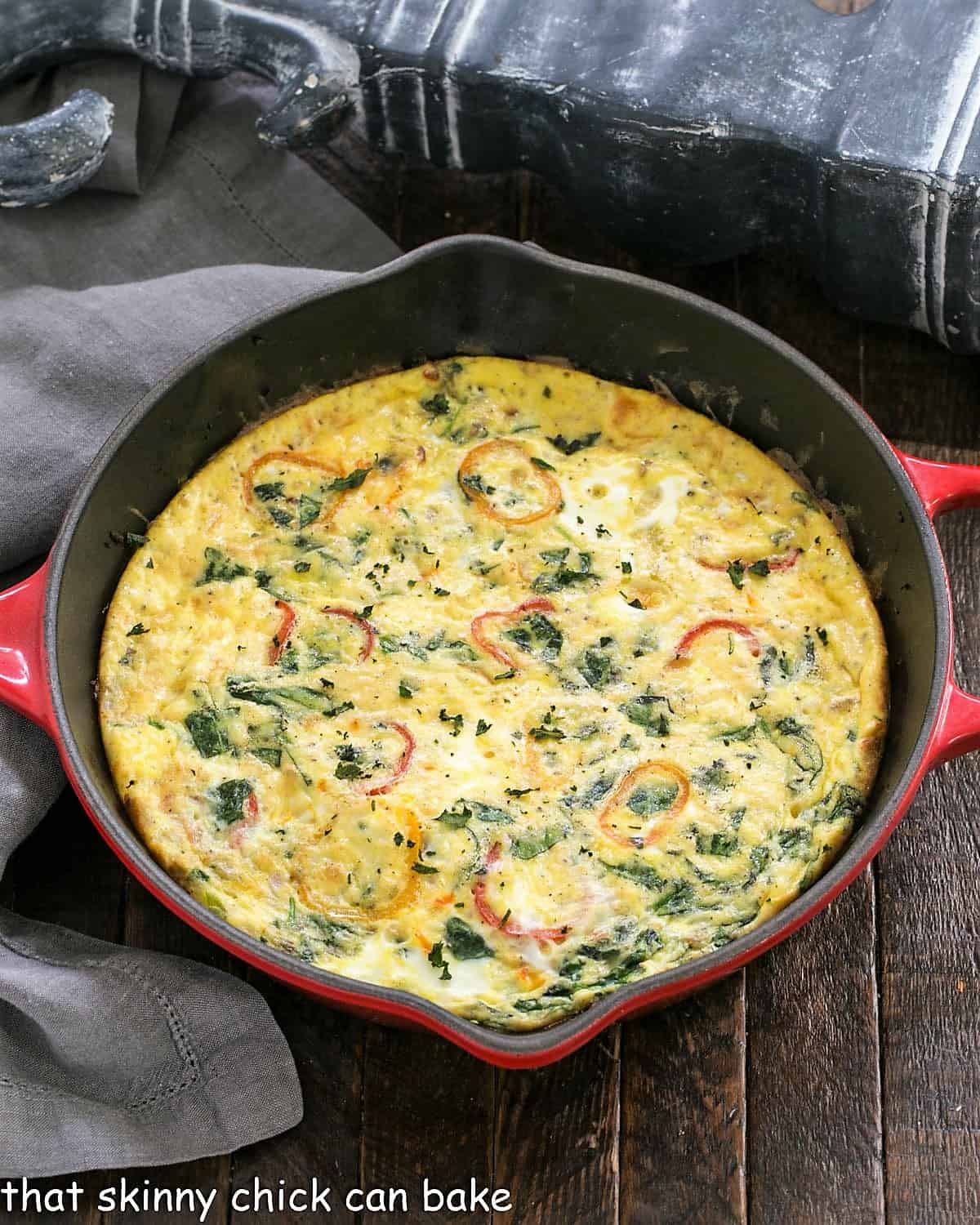 Vegetable Frittata - A versatile egg frittata with spinach and peppers. It's delicious for any meal of the day Overhead view of Spinach Frittata in a red cast iron skillet.