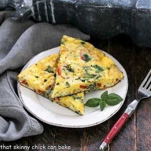 2 slices of spinach frittata on a white plate with a red handle fork