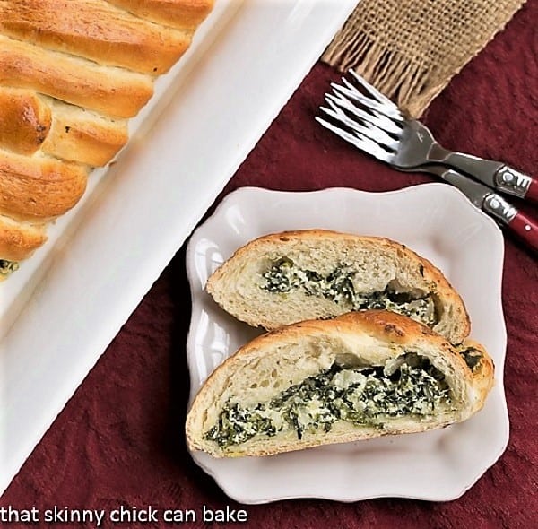 Spinach and Onion Braid slices on a square white plate with two red-handled forks.