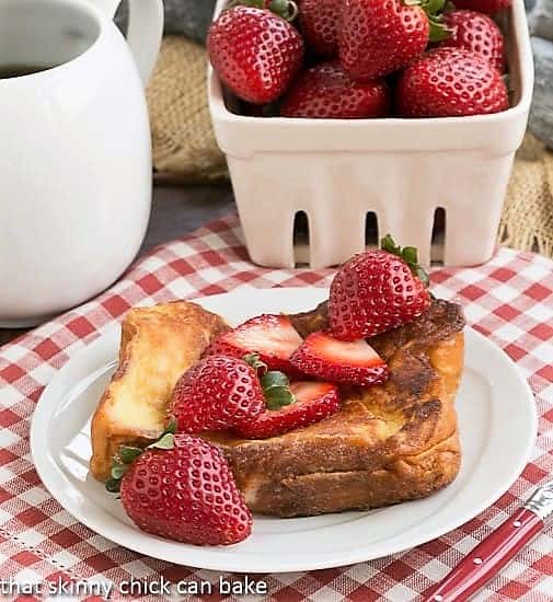 Strawberry Mascarpone Stuffed French Toast on a white plate topped with fresh strawberries.