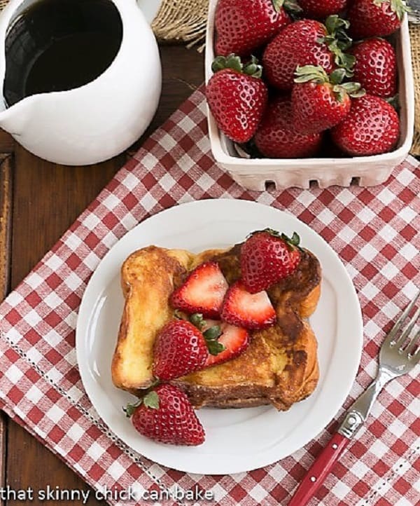 Strawberry Mascarpone Stuffed French Toast overhead view with syrup and a basket of strawberries.