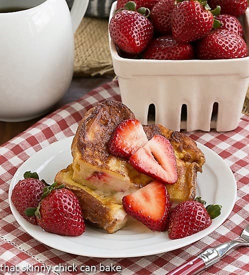 Strawberry Mascarpone Stuffed French Toast cut in half and served topped with sliced strawberries.