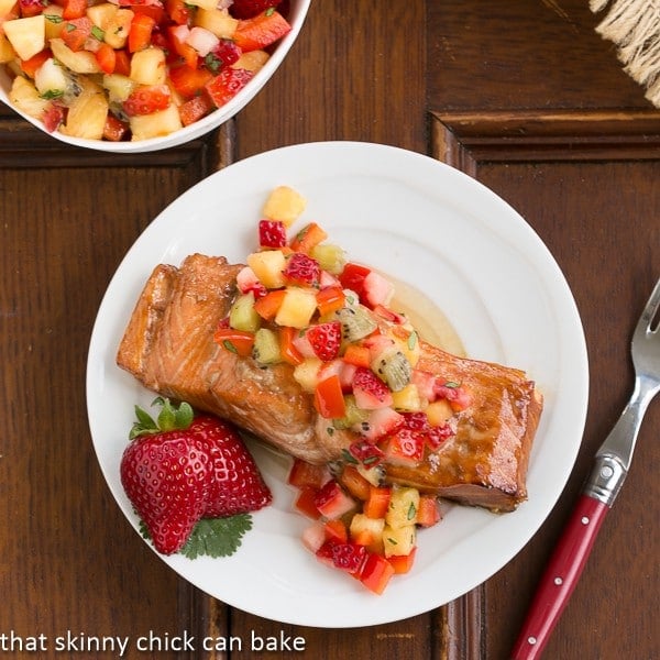 Overhead view of Strawberry Salsa Topped Salmon on a white plate with a red handled fork