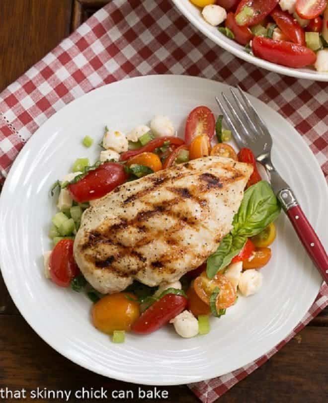 Overhead view of grilled chicken breast over a fresh Caprese salad