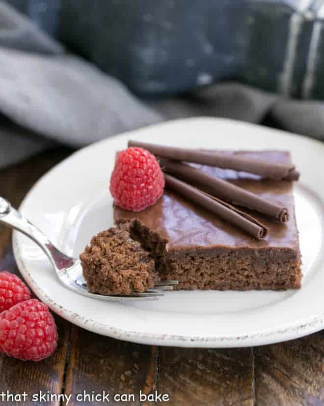 Chocolate Syrup Brownies on a round white plate with a fork with a bite of cake on the tines.