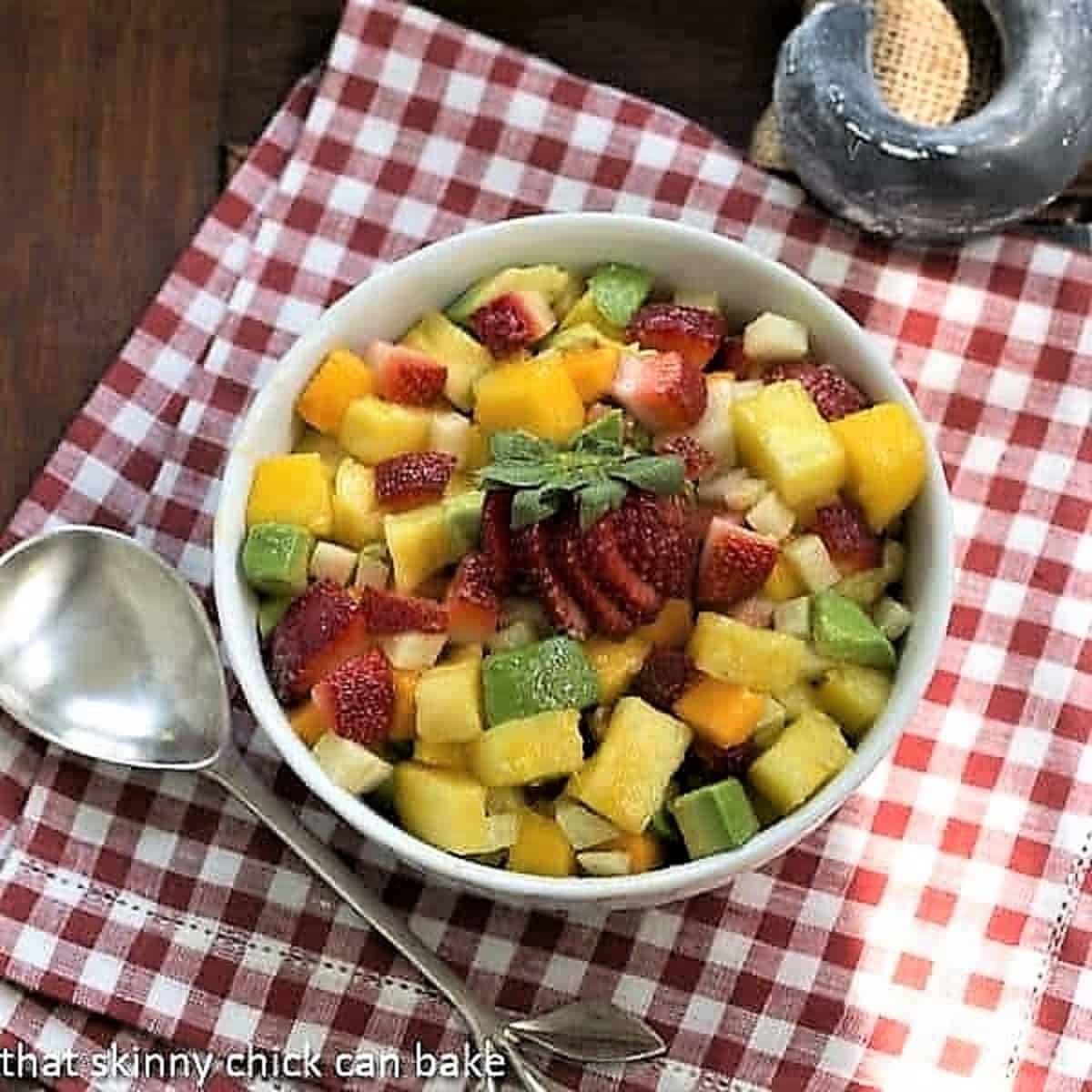 Mango Strawberry Avocado Salad in a white bowl on a red and white checked napkin.