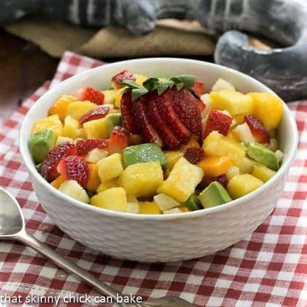 Mango Strawberry Avocado Salad in a white bowl with a silver serving spoon.