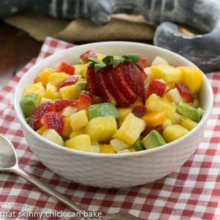 Mango Strawberry Avocado Salad in a white bowl with a silver serving spoon