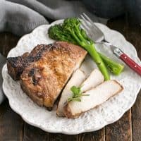 Overhead view of a plate of a sliced pork chop, broccoli and a red handled fork