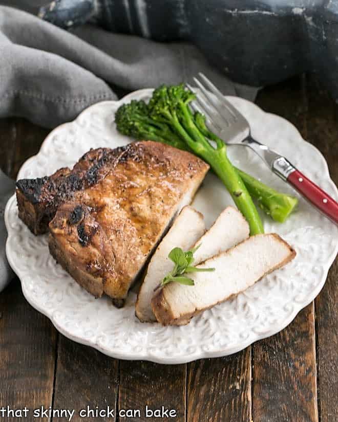 Overhead view of a plate of a sliced pork chop, broccoli and a red handled fork