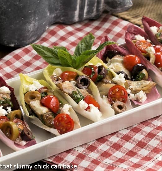 A white ceramic tray with endive leaves filled with salad.