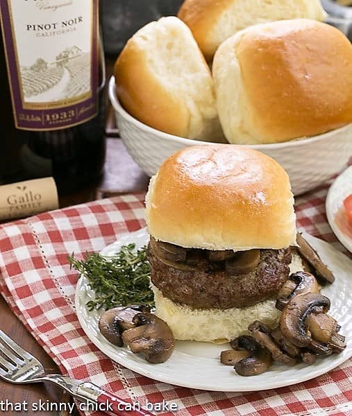 Mushroom Topped Pinot Noir Burgers on a white plate with mushrooms and herbs