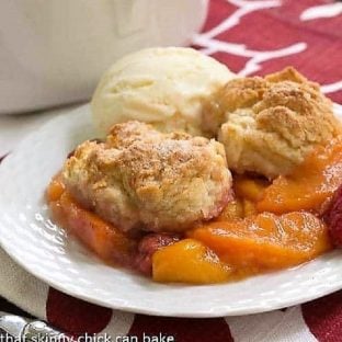 Peach Raspberry Cobbler on a white dessert plate with a scoop of vanilla ice cream
