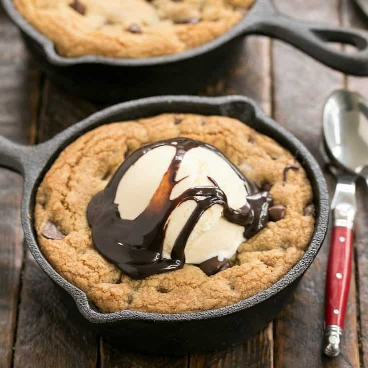 Overhead with of a pizookie topped with ice cream and fudge sauce with a red handle spoon