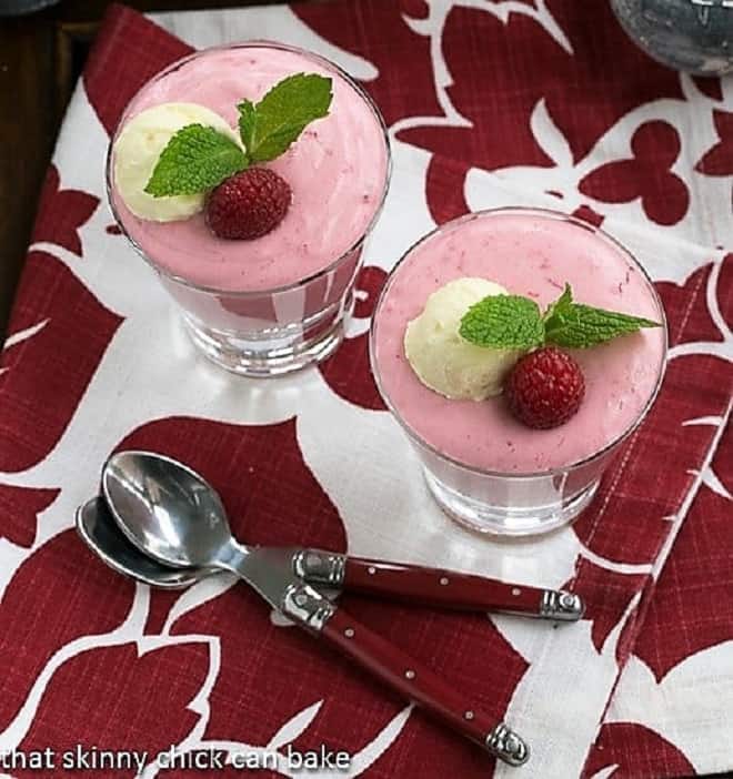 Raspberry Mousse in highball glasses viewed from above with red handled spoons over a red and white napkin