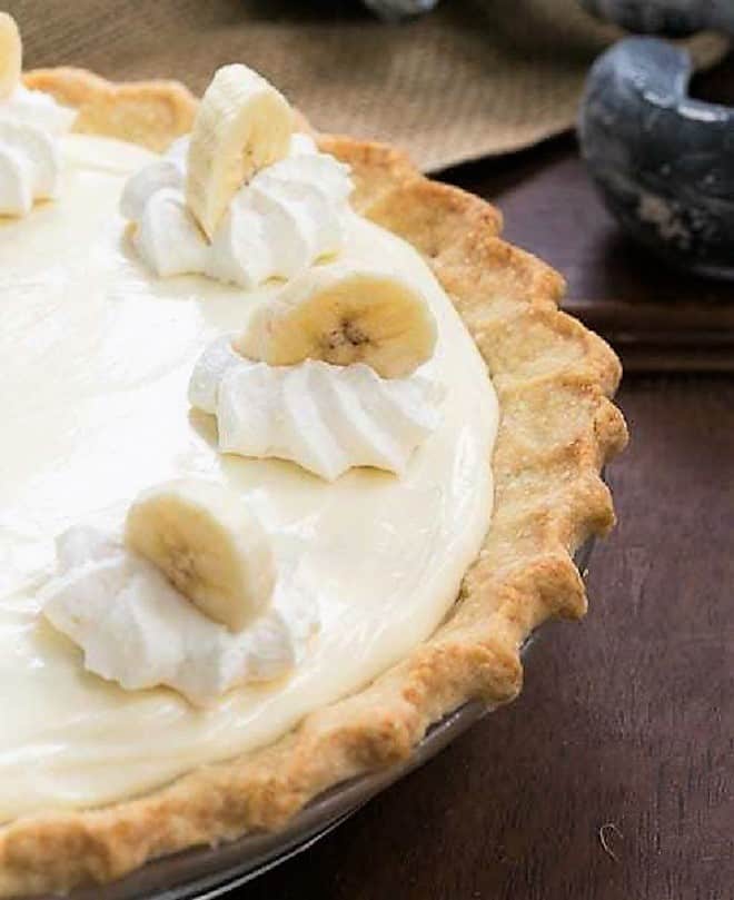 Banana Cream Cheesecake Pie close up view of pie and whipped cream and banana slice garnishes