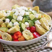 A white bowl of Greek Salad topped with feta cubes