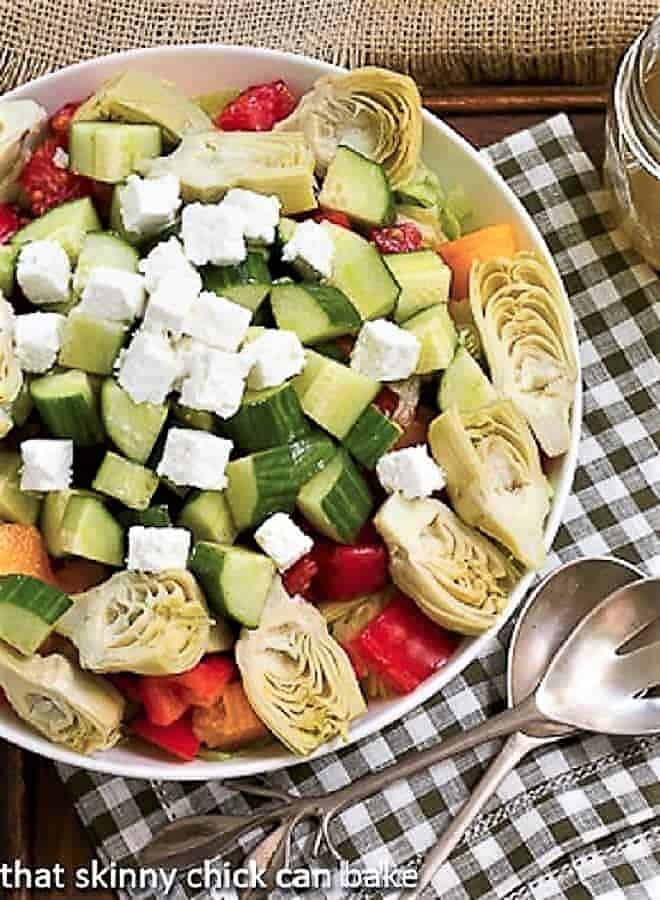 Greek Salad with Feta in a white serving bowl over a green and white checked napkin