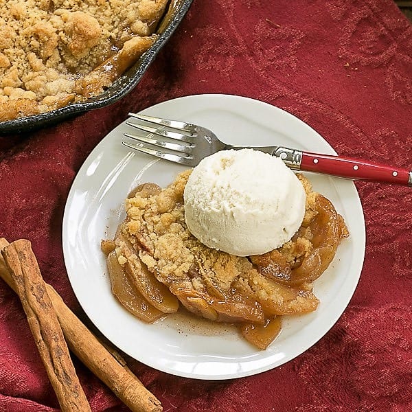 Overhead view of Grilled Apple Crisp on a round white plate with a scoop of vanilla ice cream.