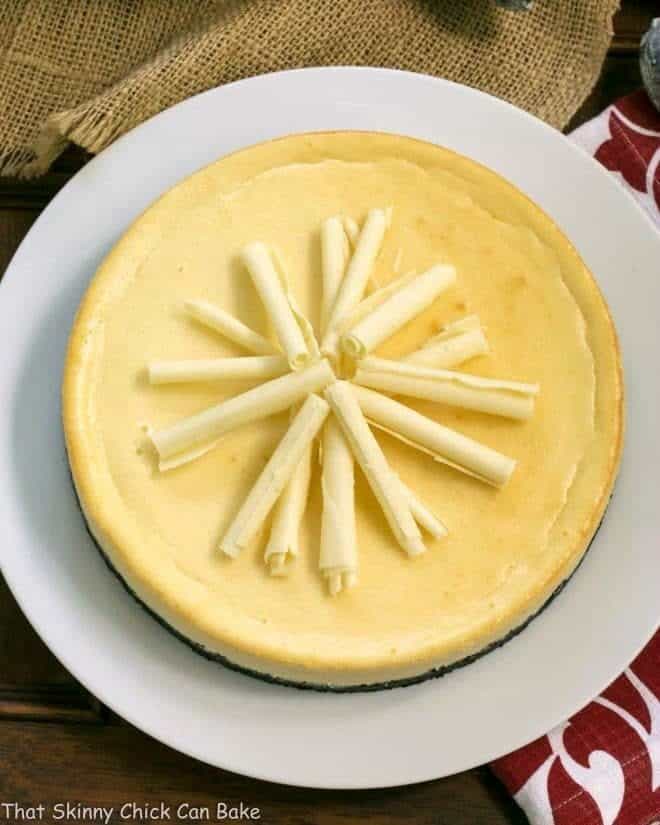 White Chocolate Cheesecake on a white serving plate topped with white chocolate curls