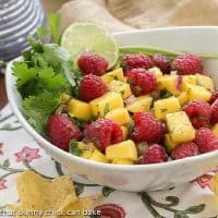 Raspberry Mango Salsa in a white bowl with cilantro and lime garnish