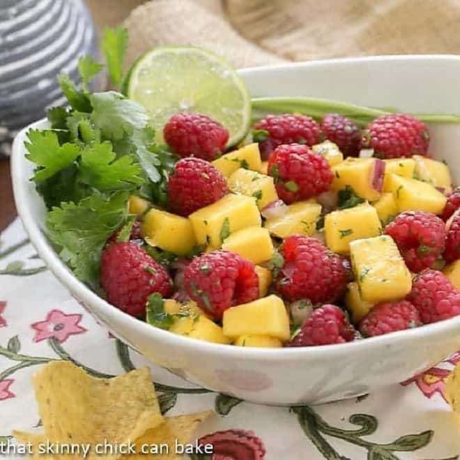  Raspberry Mango Salsa in a white bowl with cilantro and lime garnish.