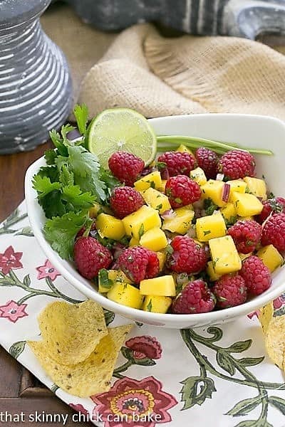  Raspberry Mango Salsa in a white bowl with cilantro and lime garnish.