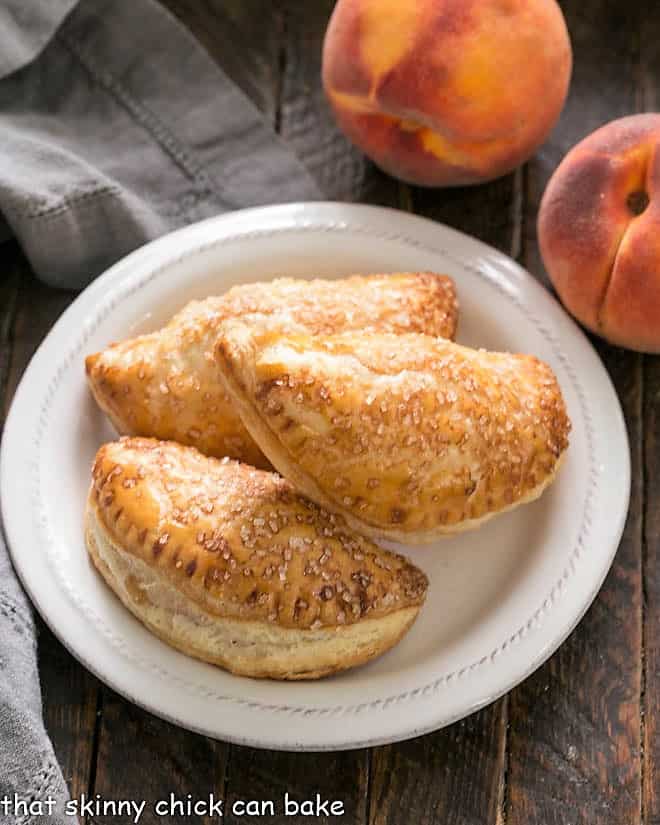 Overhead view of 3 peach turnovers on a white plate.